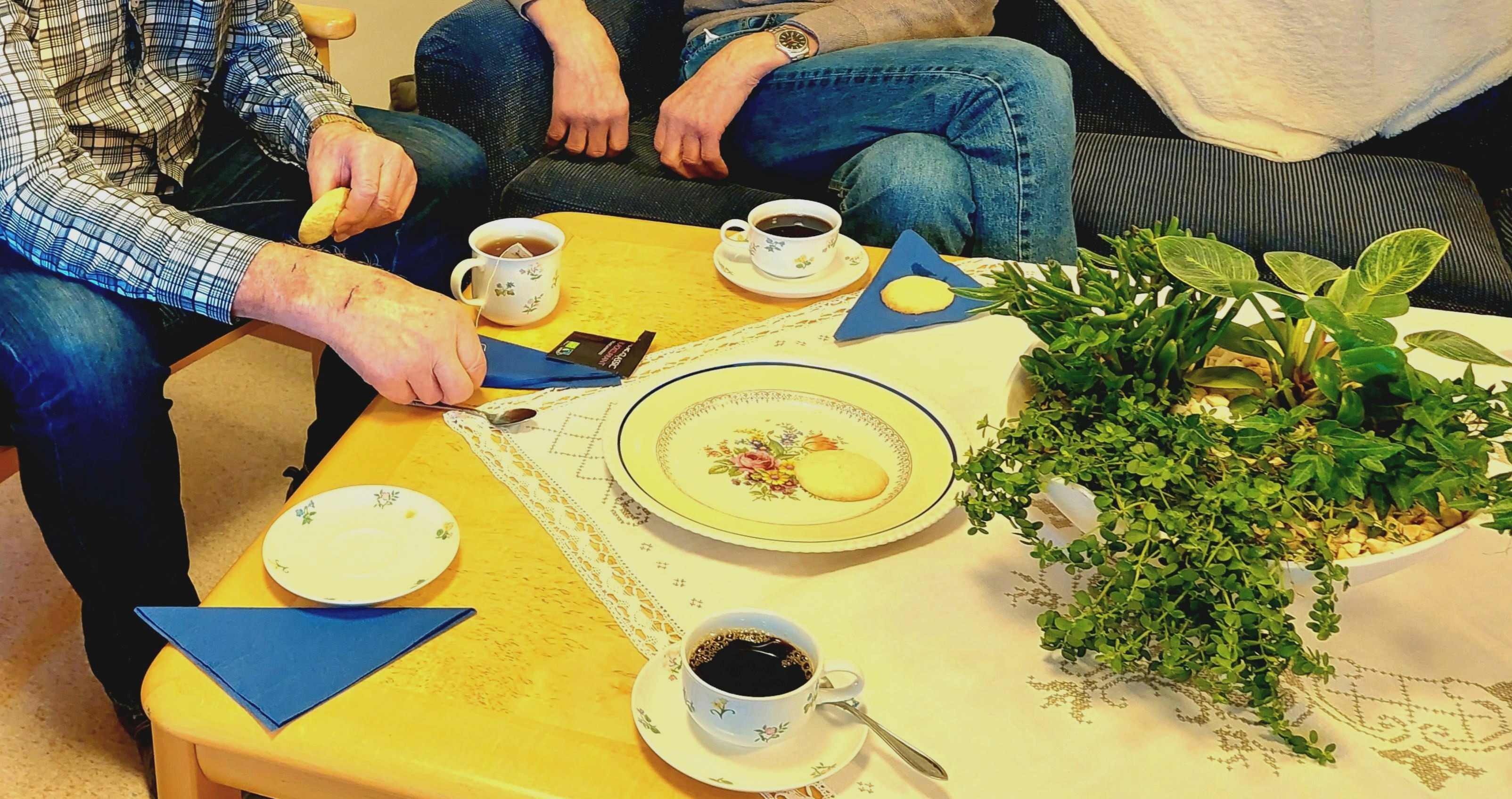 Fika är serverat på ett bord. personer sitter runt bordet.