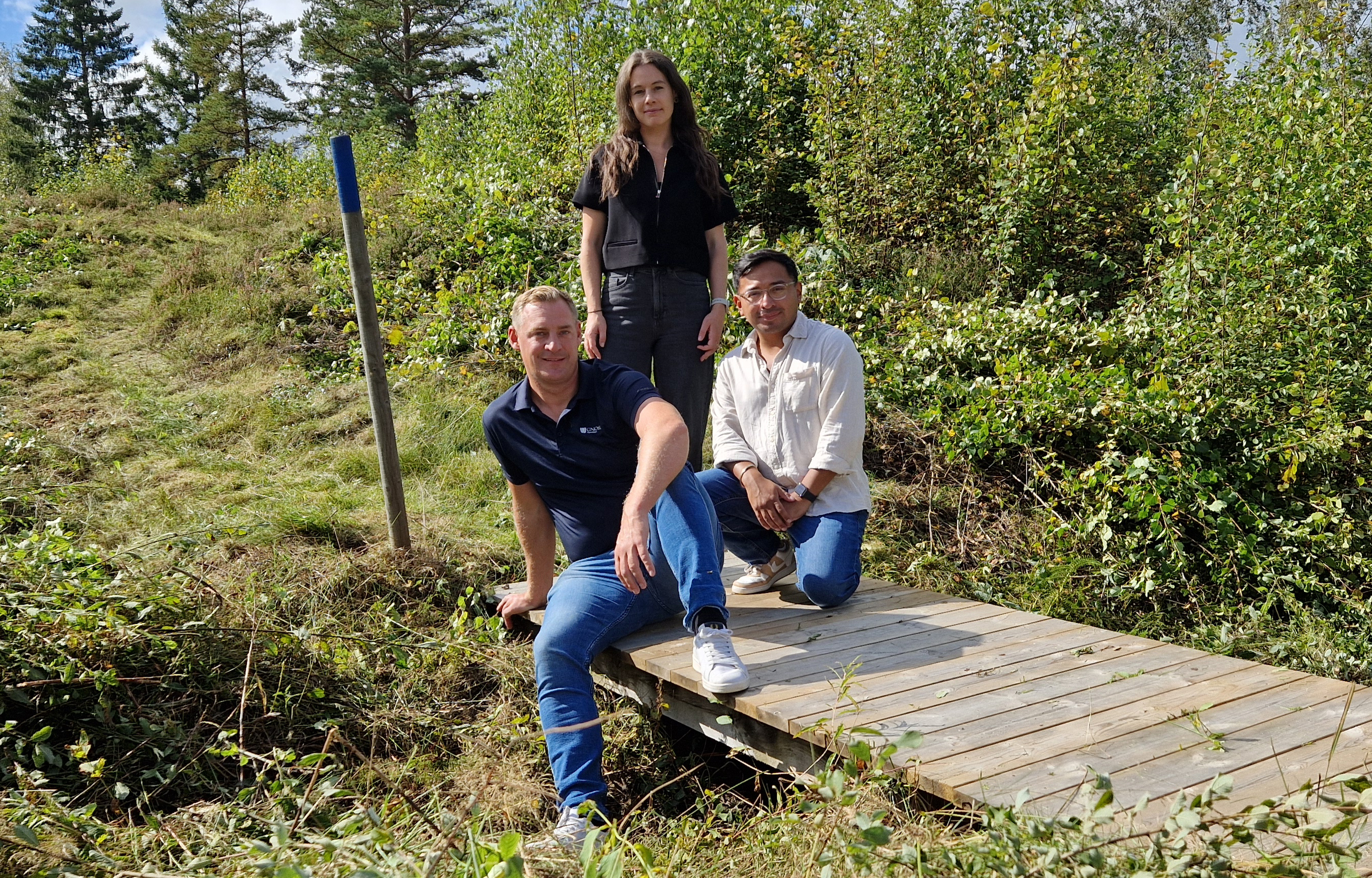 Tre personer som står på en gångbro.