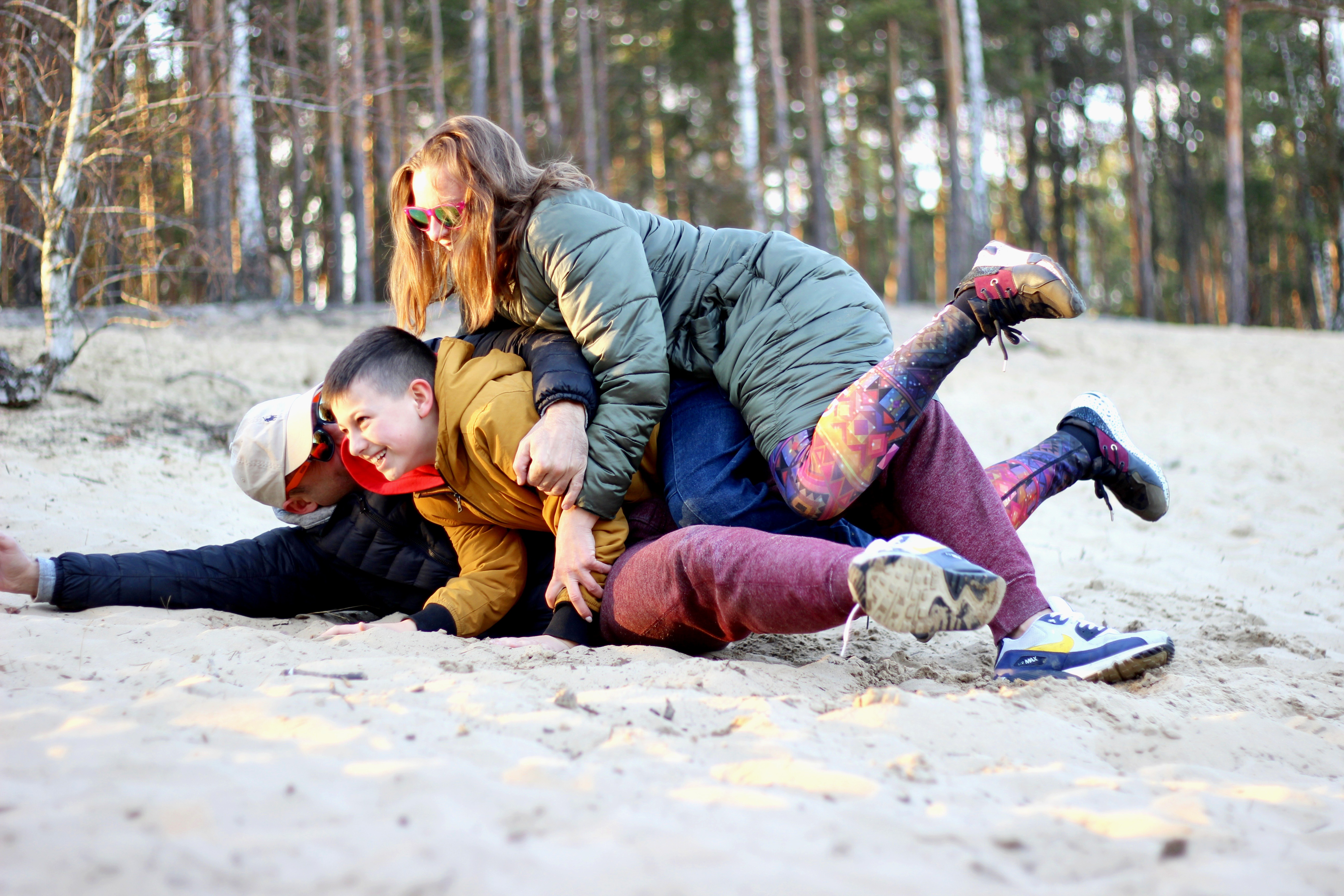 En familj leker och brottas med varandra på stranden.