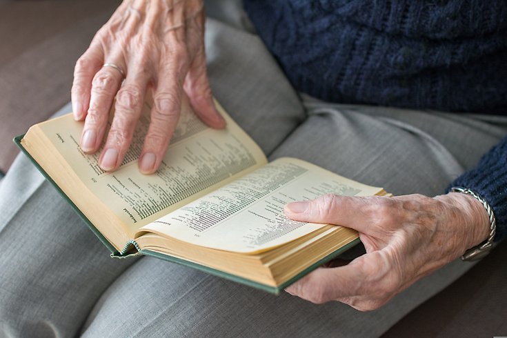 En äldre mans händer håller i en bok.