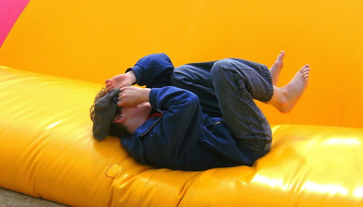 En pojke som ligger ner i en hoppborg efter att hoppat.