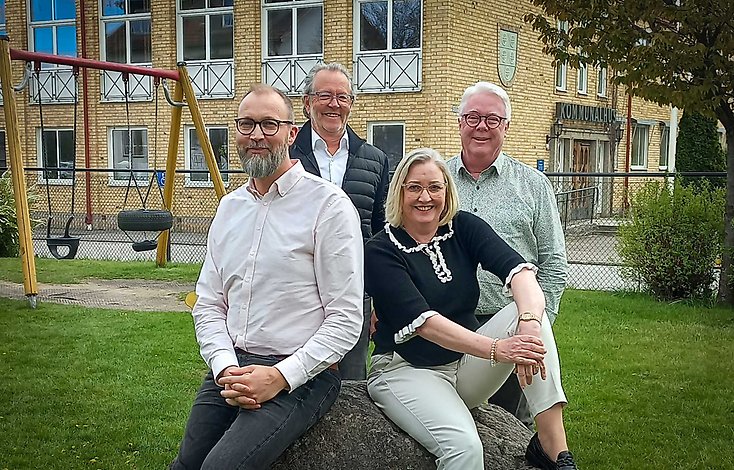 Tre män och en kvinna på lekplats utanför kommunhuset i Gnosjö.