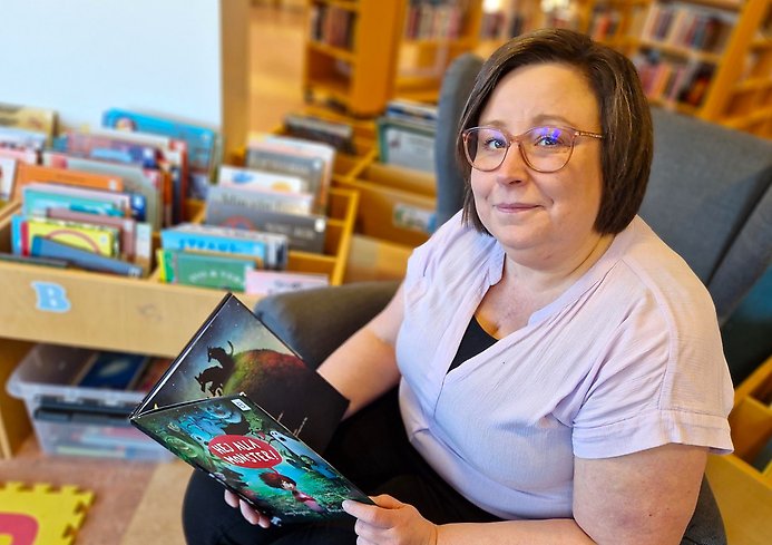 En kvinna i ett kontor, som håller bok i handen.