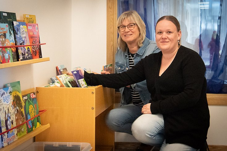 Två kvinnor framför en back med barnböcker.