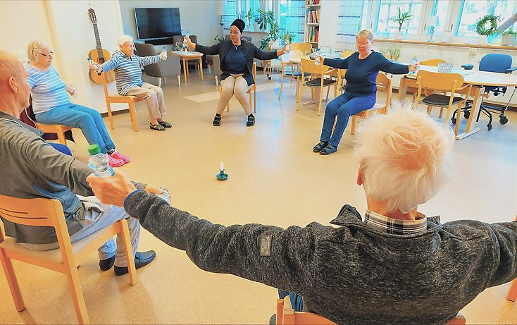 Personer sitter på stolar och tränar sina armar.