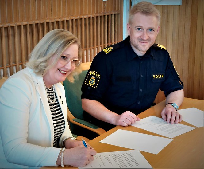 En polis och en kvinna skriver under ett papper.