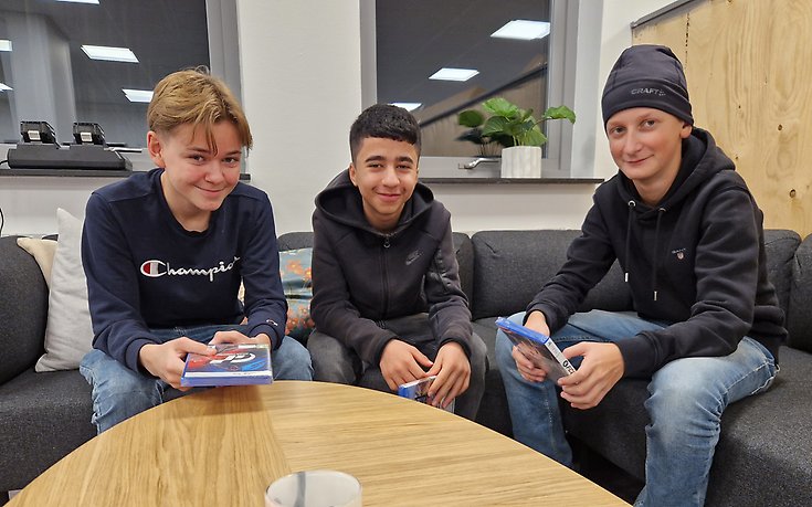 Tre tonårskillar runt ett bord. 