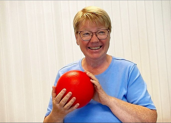 En kvinna håller i en boll och skratatr.