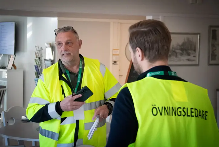 Två män i varselkläder, på ryggen står det "övningsledare".