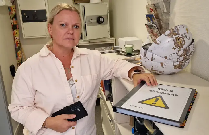 En kvinna med en pärm framför sig på en hylla.