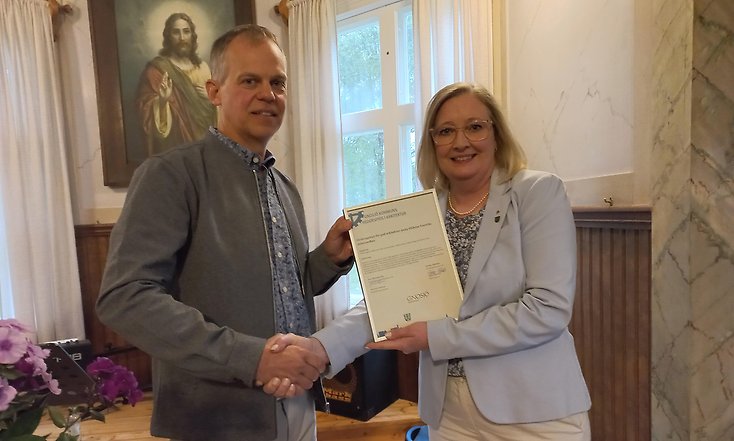 Carl Ottosson, ordförande i församlingen, tog emot diplomet av Kristine Hästmark, kommunalråd. De skakar hand.