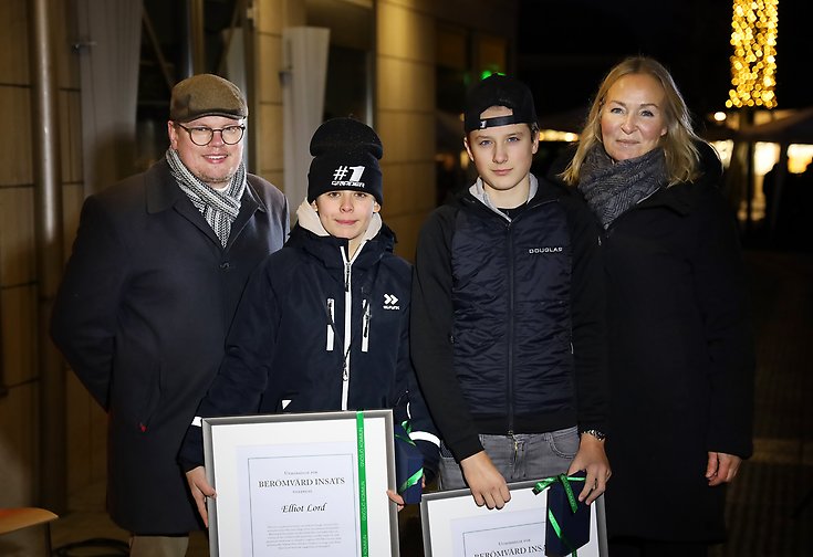 Fyra personer, de i mitten håller upp varsitt diplom.