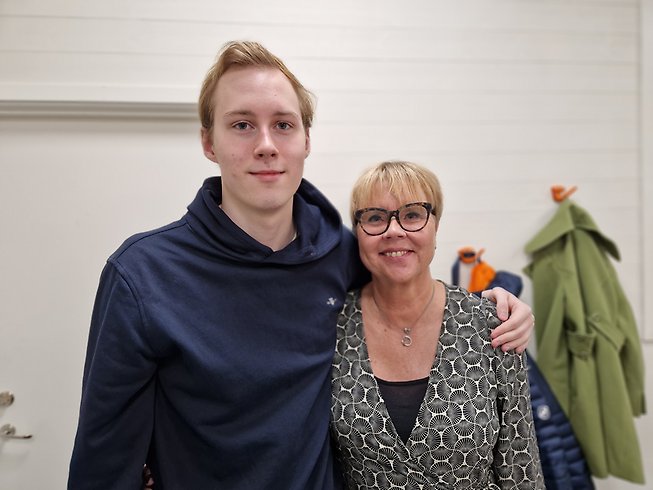 Ung kille som har lagt armen om en äldre kvinna, hans mor.