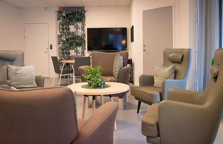 Ett gemenskapsrum, med bruna skinnfåtöljer i ring runt ett soffbord.  