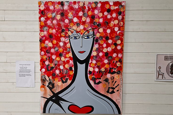 En tavla som föreställer en kvinna med stort hår och ett rött hjärta.