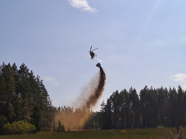 Helikopter som släpper kalk över sjö.