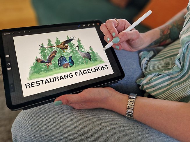 Elin håller i den lilla Ipaden när hon tecknar i programmet.
