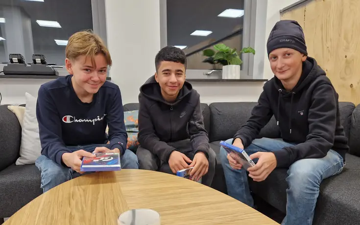 Tre tonårskillar runt ett bord.