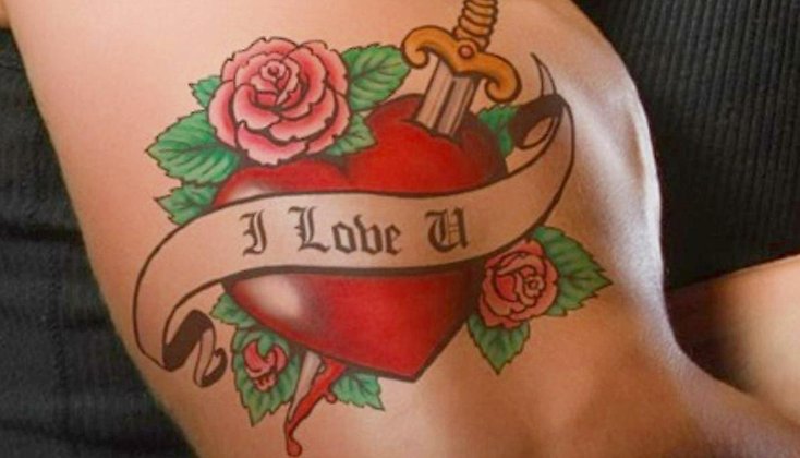 En arm med en tatuering föreställande ett hjärta med en kniv som går igenom det.