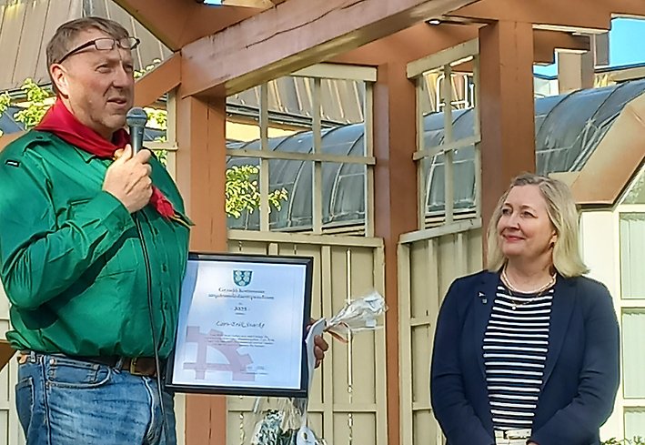 En manlig scoutledare får diplom av en kvinna.