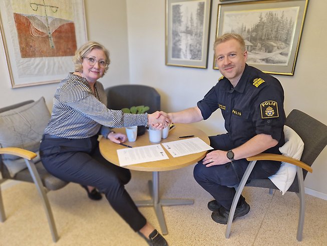 Kristine Hästmark och Anders Sund sitter vid ett bord och skakar hand.